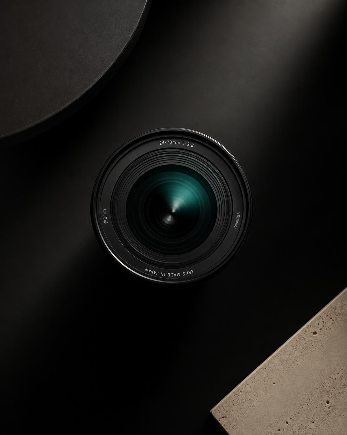 A camera lens on a black surface, its glass catching a teal reflection